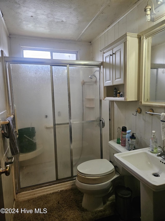 bathroom featuring toilet, a shower with door, and a textured ceiling