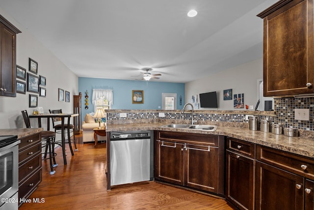 kitchen with tasteful backsplash, dark brown cabinets, stainless steel appliances, sink, and hardwood / wood-style flooring