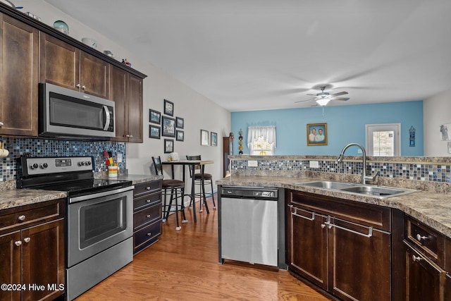 kitchen featuring tasteful backsplash, dark brown cabinetry, stainless steel appliances, sink, and light hardwood / wood-style floors