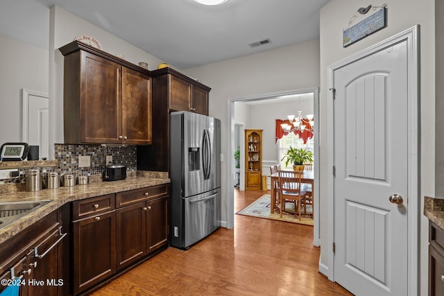 kitchen featuring tasteful backsplash, dark brown cabinetry, a chandelier, stainless steel fridge with ice dispenser, and light hardwood / wood-style floors