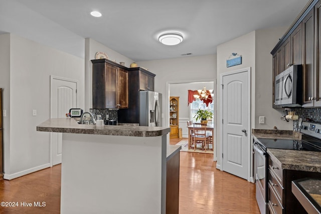 kitchen featuring kitchen peninsula, light hardwood / wood-style flooring, decorative backsplash, appliances with stainless steel finishes, and dark brown cabinetry