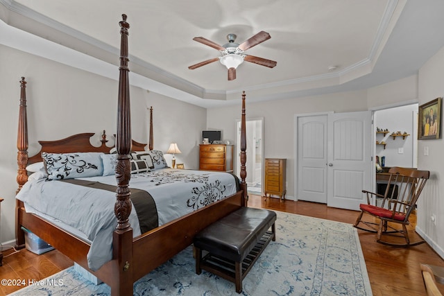 bedroom featuring hardwood / wood-style floors, a tray ceiling, ceiling fan, and crown molding