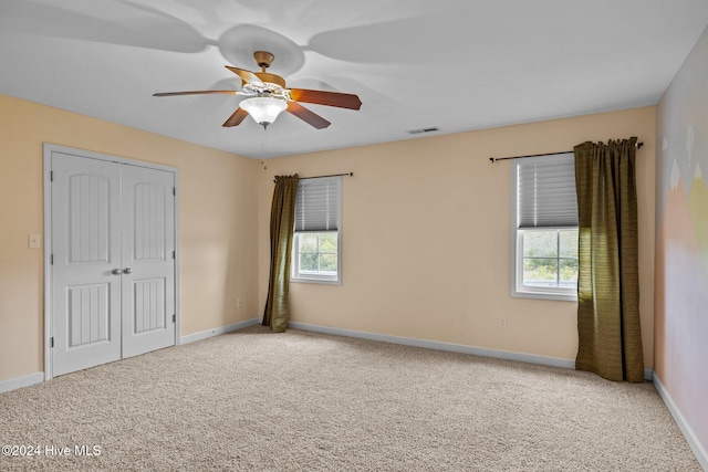 unfurnished bedroom featuring ceiling fan, a closet, and carpet