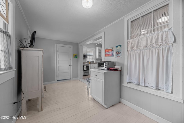 kitchen featuring white cabinets, a textured ceiling, stainless steel range, and crown molding