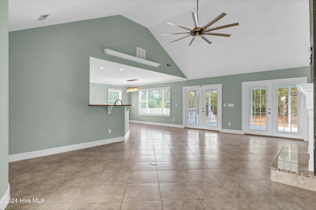 unfurnished living room featuring french doors, plenty of natural light, light tile patterned floors, and high vaulted ceiling