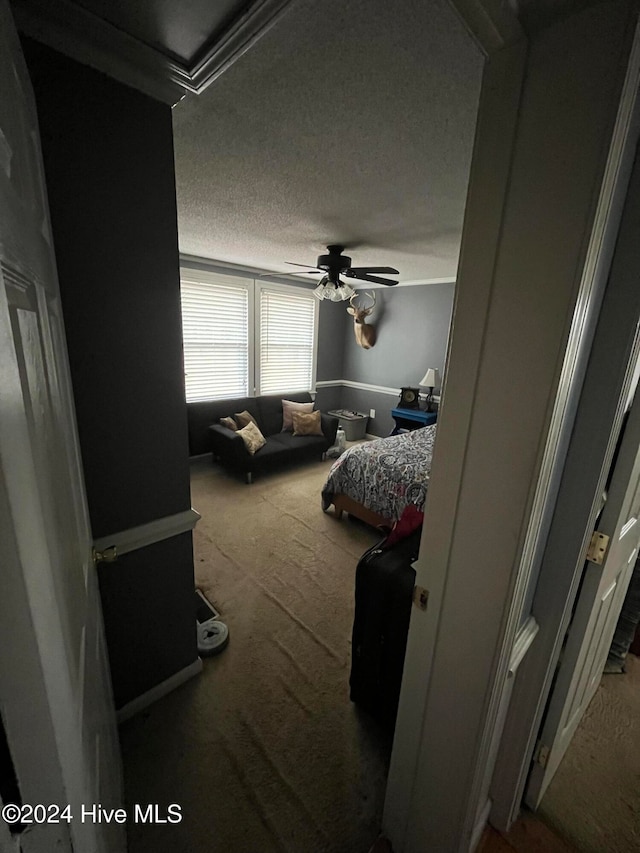 bedroom featuring a textured ceiling, carpet floors, ceiling fan, and ornamental molding