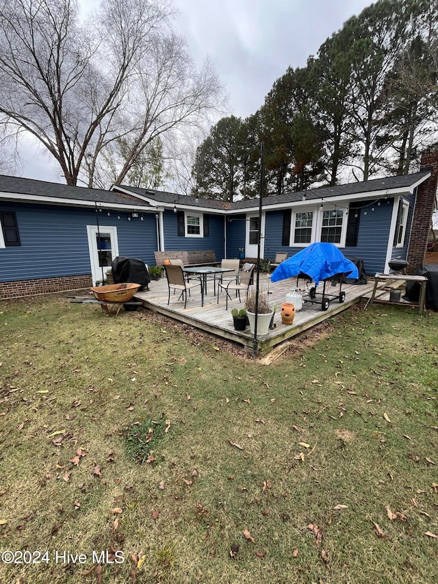 back of property with a wooden deck and a lawn