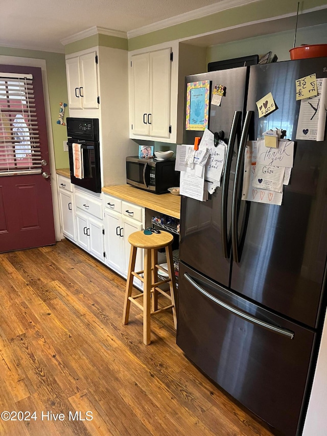 kitchen featuring stainless steel appliances, white cabinetry, hardwood / wood-style flooring, and crown molding