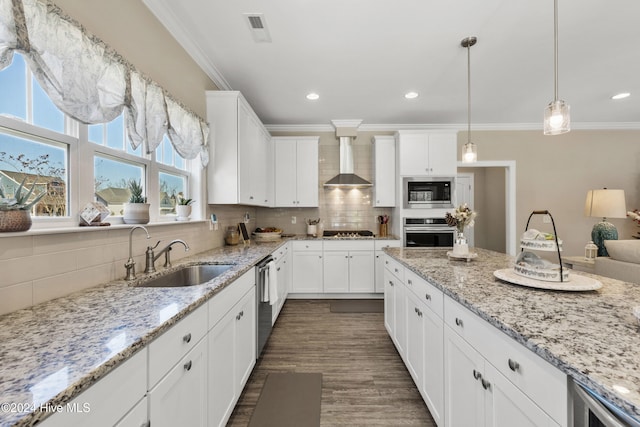 kitchen featuring tasteful backsplash, wall chimney range hood, sink, white cabinetry, and appliances with stainless steel finishes