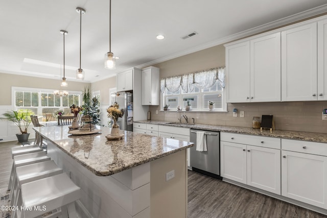 kitchen featuring white cabinets, appliances with stainless steel finishes, pendant lighting, and a center island