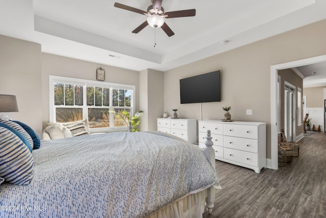 bedroom with hardwood / wood-style flooring, ceiling fan, crown molding, and a raised ceiling