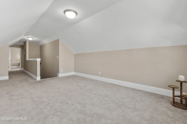 additional living space with light colored carpet and lofted ceiling