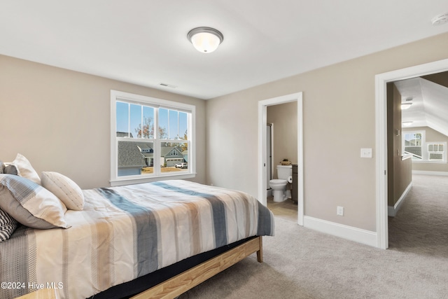 bedroom with light carpet, connected bathroom, and multiple windows