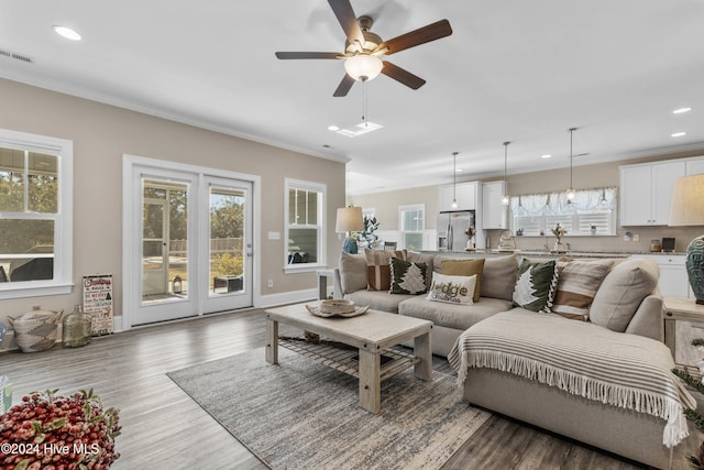 living room with ceiling fan, dark hardwood / wood-style floors, ornamental molding, and a healthy amount of sunlight