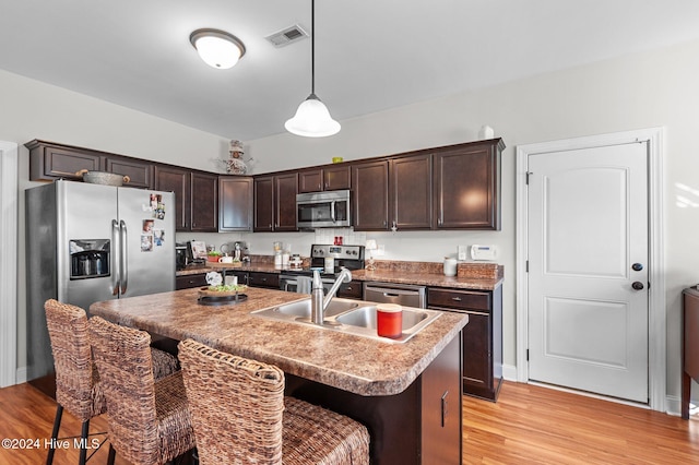 kitchen with stainless steel appliances, light hardwood / wood-style flooring, a kitchen island with sink, and sink