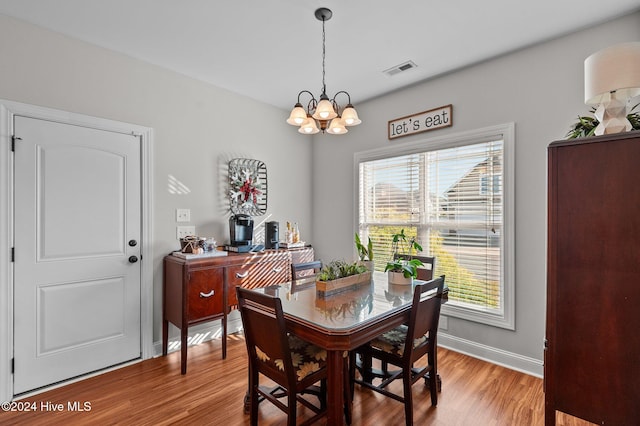 dining area featuring hardwood / wood-style floors and an inviting chandelier