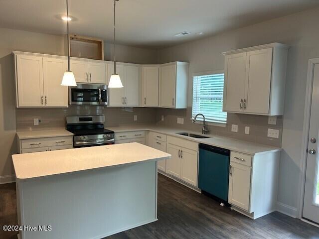 kitchen featuring white cabinets, decorative light fixtures, and appliances with stainless steel finishes