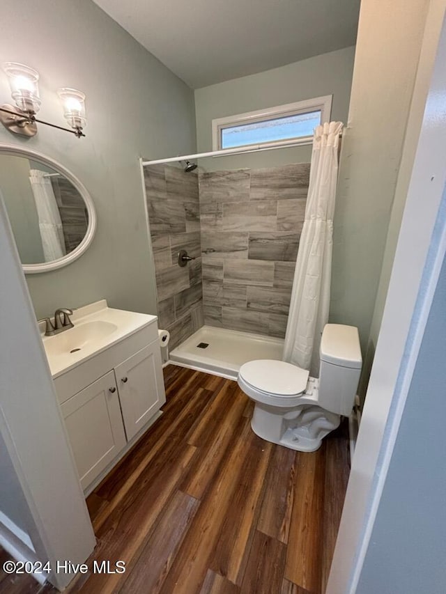 bathroom with hardwood / wood-style flooring, vanity, curtained shower, and toilet