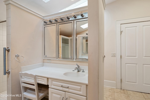 bathroom with tile patterned flooring, vanity, and vaulted ceiling with skylight