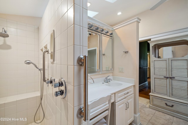 bathroom featuring vaulted ceiling with skylight, vanity, tile patterned floors, and a tile shower