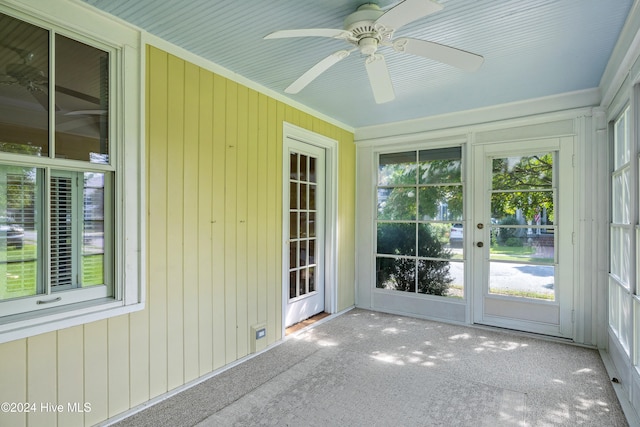 unfurnished sunroom featuring ceiling fan and plenty of natural light