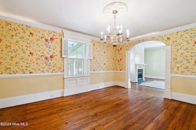 unfurnished dining area featuring dark wood-type flooring, a chandelier, and crown molding