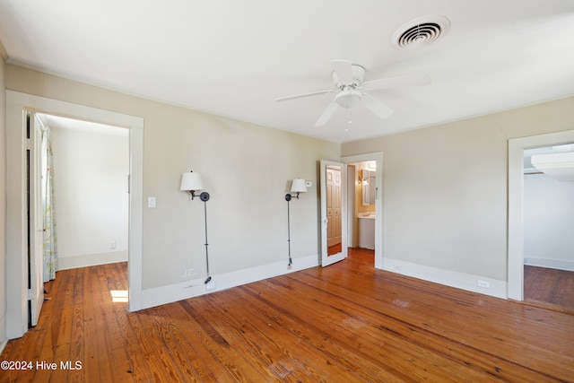 unfurnished bedroom with wood-type flooring, ceiling fan, and ensuite bath