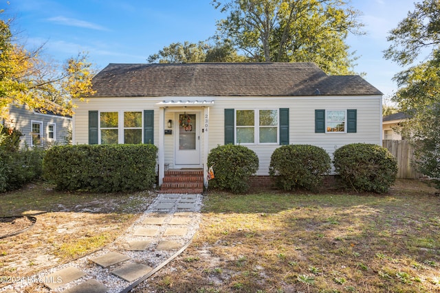 view of front of property featuring a front lawn, roof with shingles, and fence