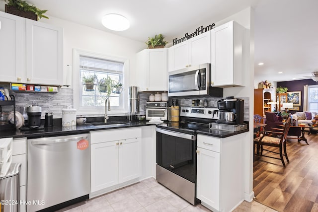 kitchen with dark countertops, decorative backsplash, appliances with stainless steel finishes, and a sink