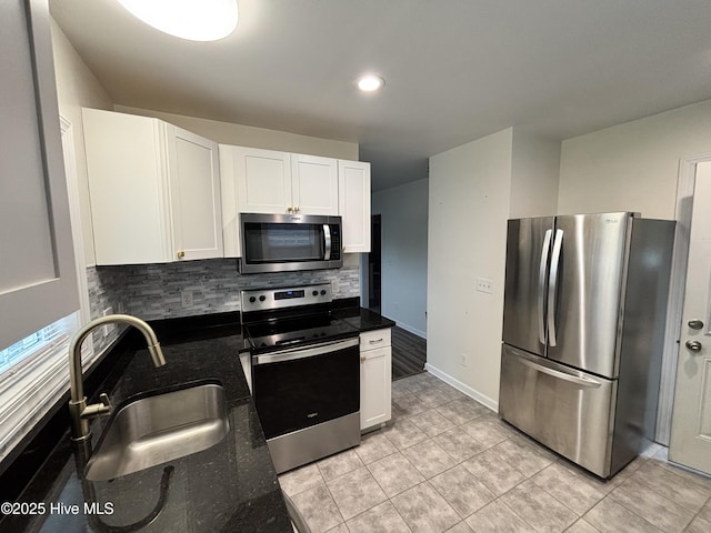 kitchen with a sink, decorative backsplash, light tile patterned floors, white cabinetry, and appliances with stainless steel finishes