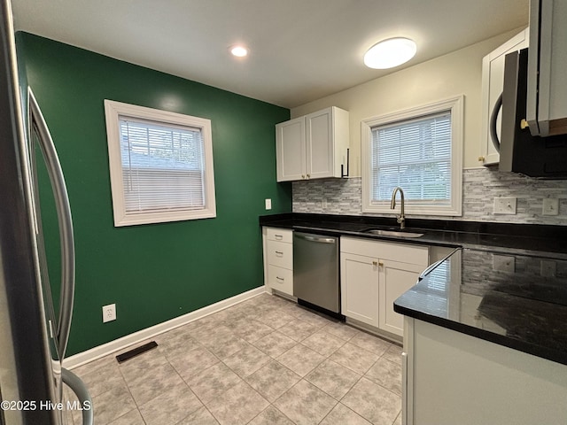 kitchen featuring backsplash, stainless steel dishwasher, a sink, and a wealth of natural light