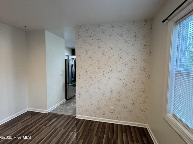 spare room with wallpapered walls, baseboards, and dark wood-style flooring