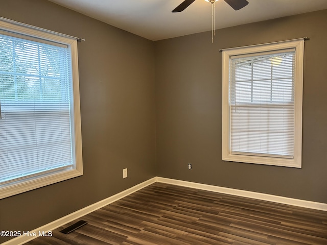 unfurnished room with baseboards, a wealth of natural light, dark wood-style floors, and ceiling fan
