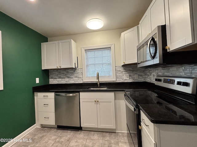 kitchen with light tile patterned floors, a sink, white cabinets, appliances with stainless steel finishes, and backsplash