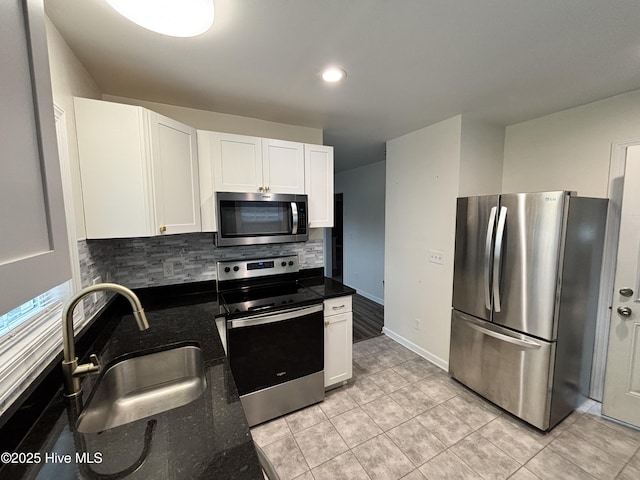 kitchen featuring a sink, backsplash, white cabinetry, stainless steel appliances, and light tile patterned flooring