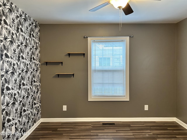 empty room with wood finished floors, a ceiling fan, and baseboards