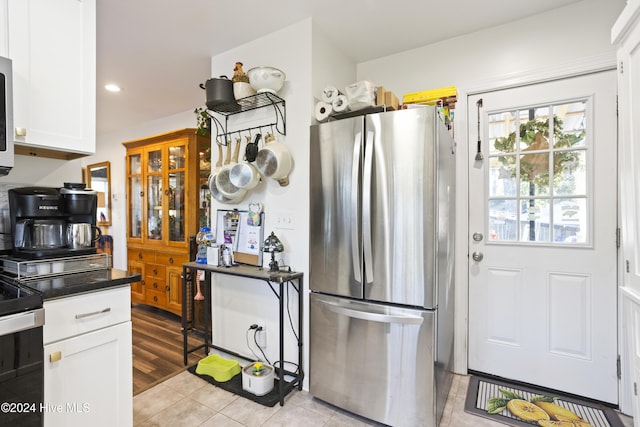 kitchen featuring dark countertops, electric range oven, recessed lighting, freestanding refrigerator, and white cabinetry