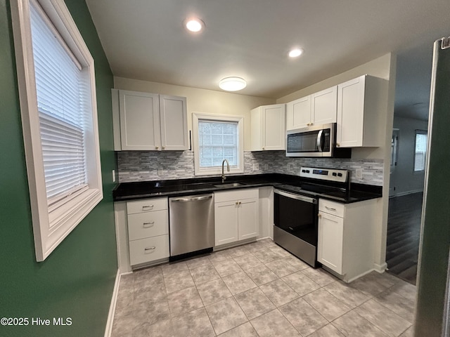 kitchen featuring dark countertops, white cabinetry, stainless steel appliances, and a sink