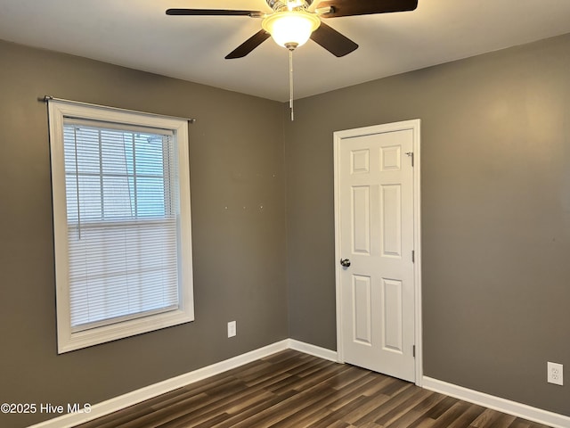 unfurnished room with dark wood-style floors, ceiling fan, and baseboards