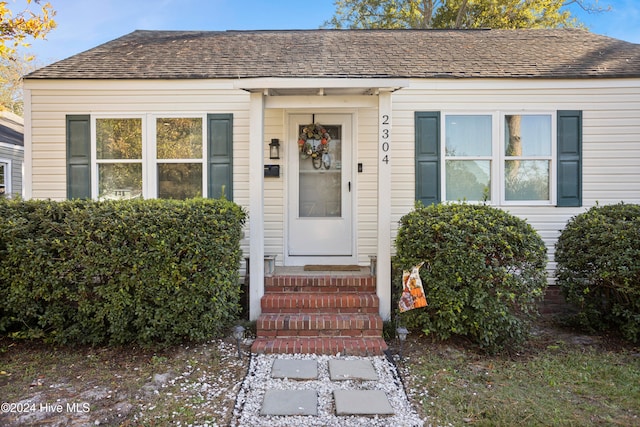 doorway to property featuring roof with shingles