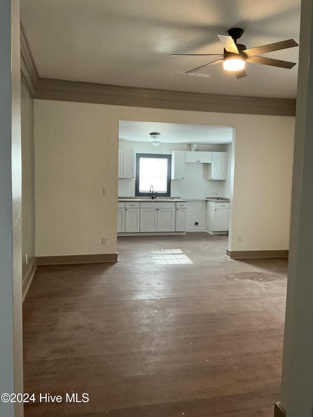 unfurnished living room featuring ceiling fan, crown molding, light wood-type flooring, and sink