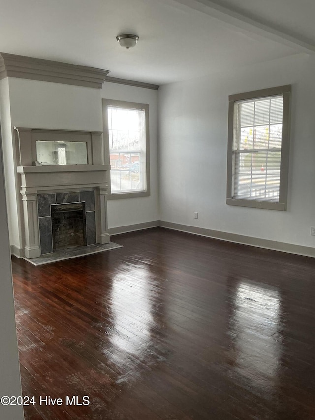 unfurnished living room featuring a tile fireplace, crown molding, and dark hardwood / wood-style flooring