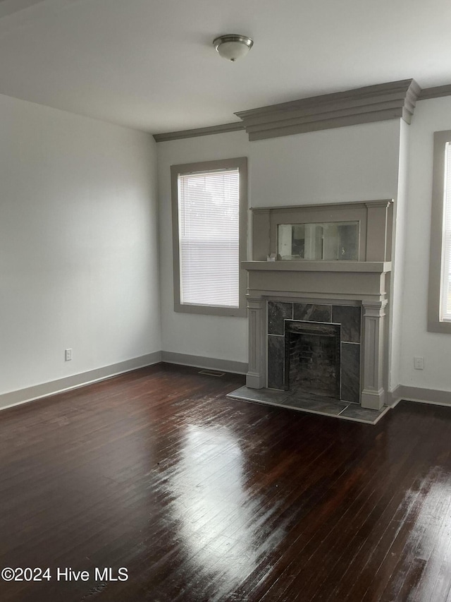 unfurnished living room with dark hardwood / wood-style floors, ornamental molding, and a fireplace