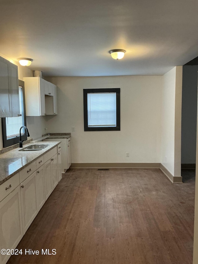 kitchen featuring white cabinets, wood-type flooring, light stone countertops, and sink