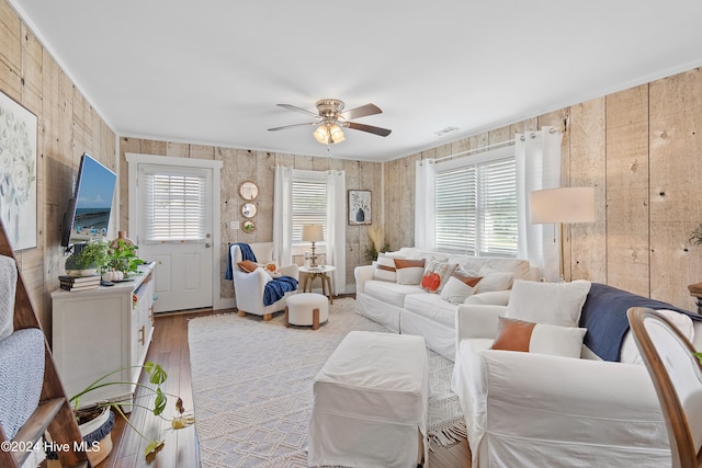 living room featuring wood walls, ceiling fan, and light hardwood / wood-style flooring