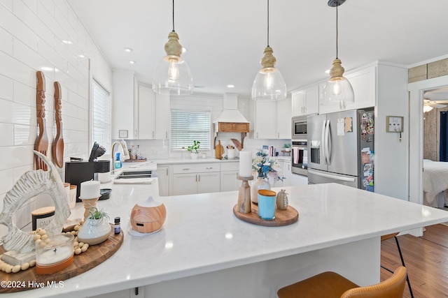 kitchen featuring appliances with stainless steel finishes, decorative light fixtures, sink, hardwood / wood-style flooring, and white cabinets