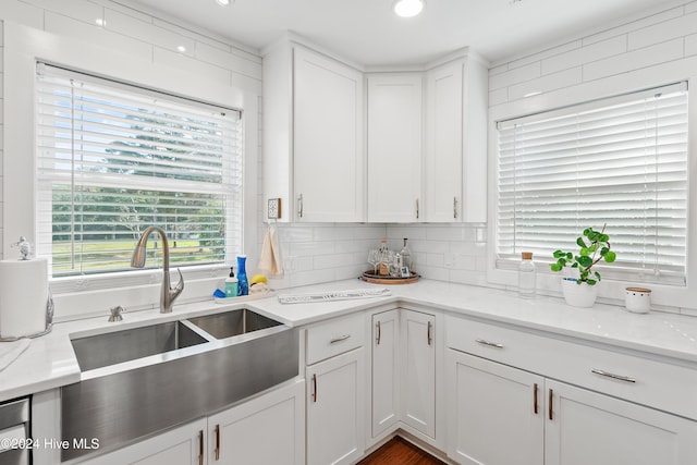 kitchen with white cabinetry, tasteful backsplash, sink, and light stone counters