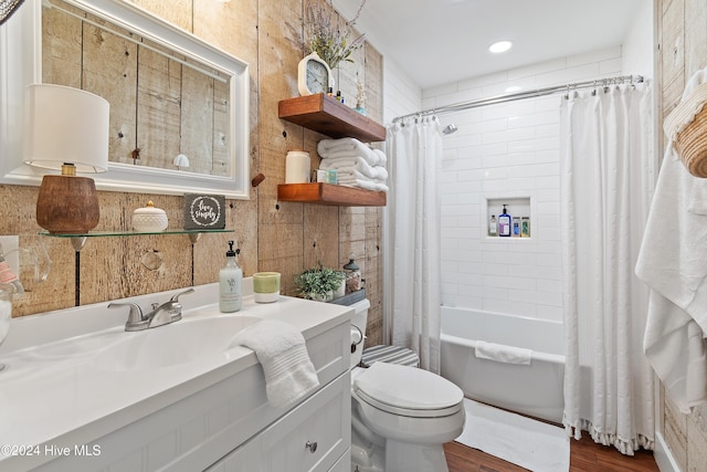 full bathroom with tile walls, vanity, hardwood / wood-style flooring, toilet, and shower / bath combo with shower curtain