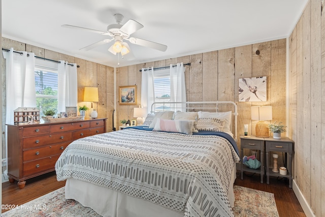 bedroom with wood walls, dark wood-type flooring, and ceiling fan