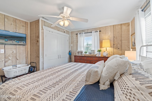 bedroom featuring wood walls, a closet, ceiling fan, and crown molding